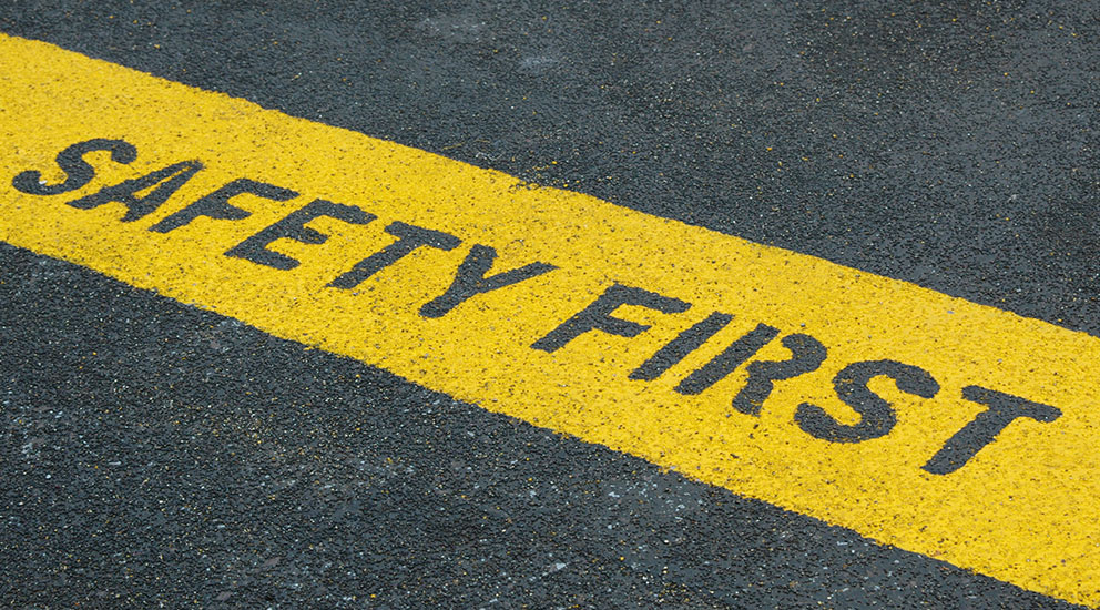 Pavement with yellow strip with “safety first” outlined
