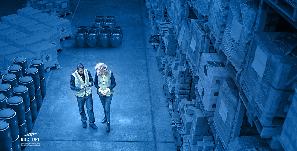 Intérieur d’un entrepôt avec deux employés marchant et examinant le système de gestion d’entrepôt